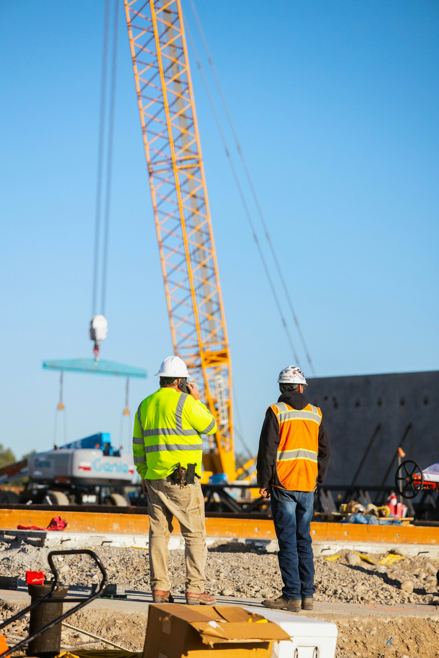 Construction workers supervising crane operations at a building site representing Saudi Arabia's 13 million foreign workers facing wartime uncertainty
