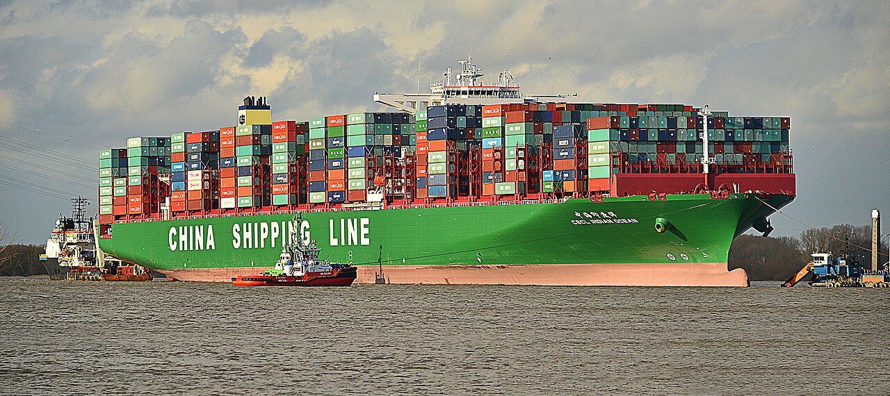 A large container ship loaded with cargo containers at sea, representing the commercial shipping vessels targeted by Iranian forces in the Strait of Hormuz