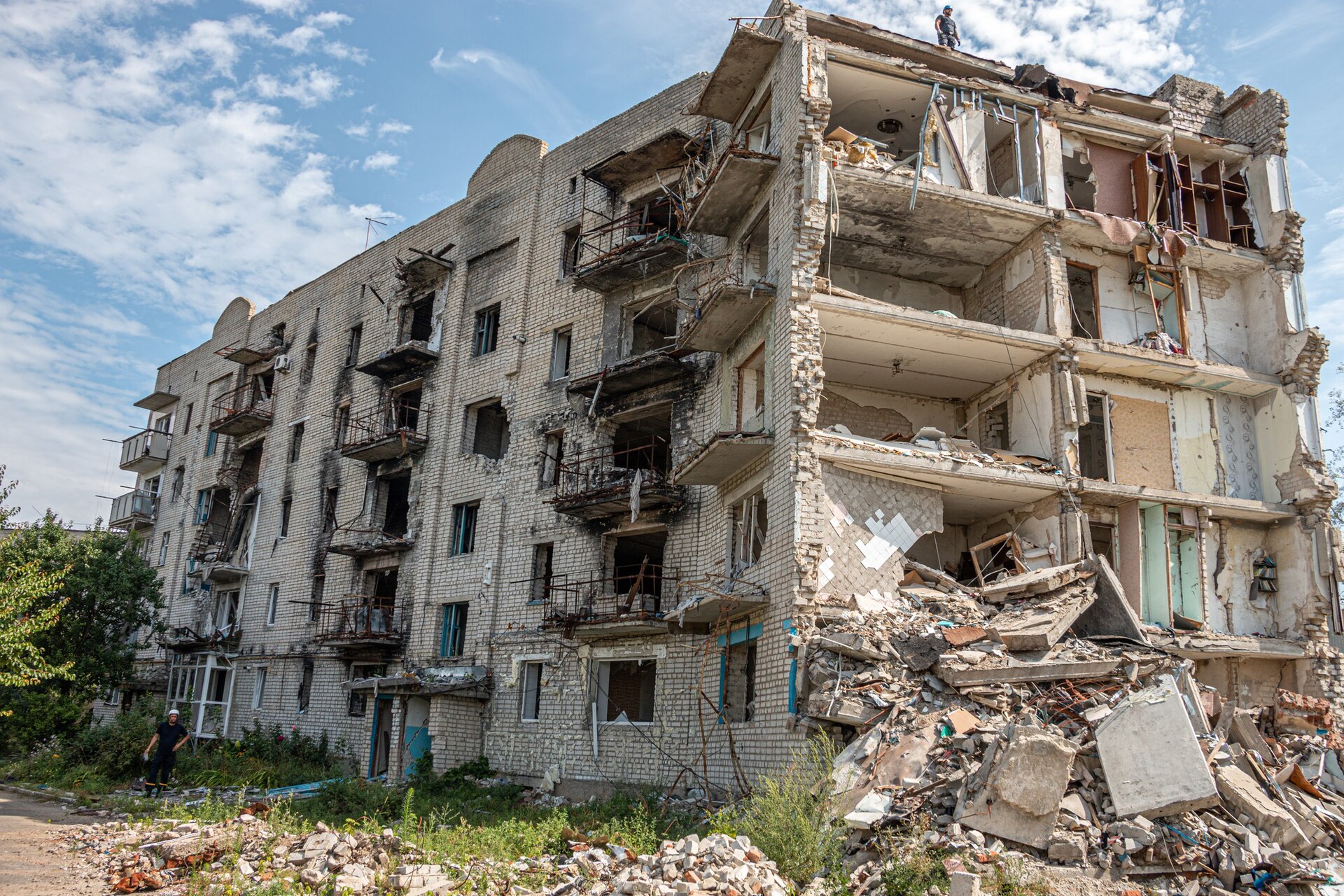 A residential apartment building destroyed by aerial bombardment, showing collapsed floors and rubble. Similar destruction was documented at Resalat Square in Tehran after strikes on March 10 and March 21, 2026. Photo: Wikimedia Commons / CC BY 4.0