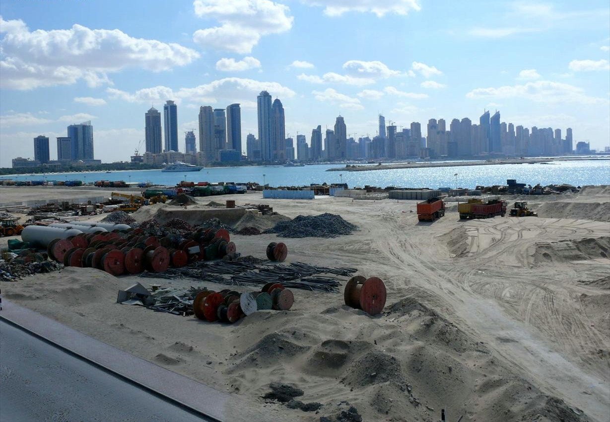 Palm Jumeirah construction site with Dubai Marina skyline and cranes in the background, showing the scale of Gulf infrastructure development. Photo: Wikimedia Commons / CC BY-SA 3.0
