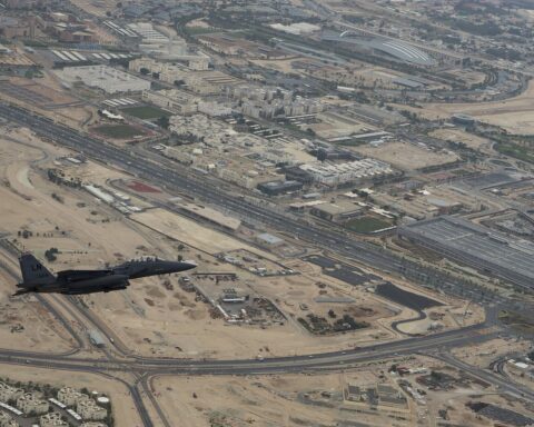 Aerial view of Qatar Education City campus complex in Al Rayyan with a U.S. Air Force F-15E Strike Eagle flying overhead during a formation flyover