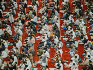 Thousands of Muslim worshippers gathered for Eid al-Fitr prayer in a grand mosque, seated on red carpets in rows during the 2026 wartime celebration