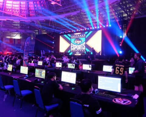 Esports tournament arena with competitors at gaming stations under stage lighting, representing Saudi Arabia billion-dollar gaming investment. Photo: Wikimedia Commons / CC BY-SA 4.0