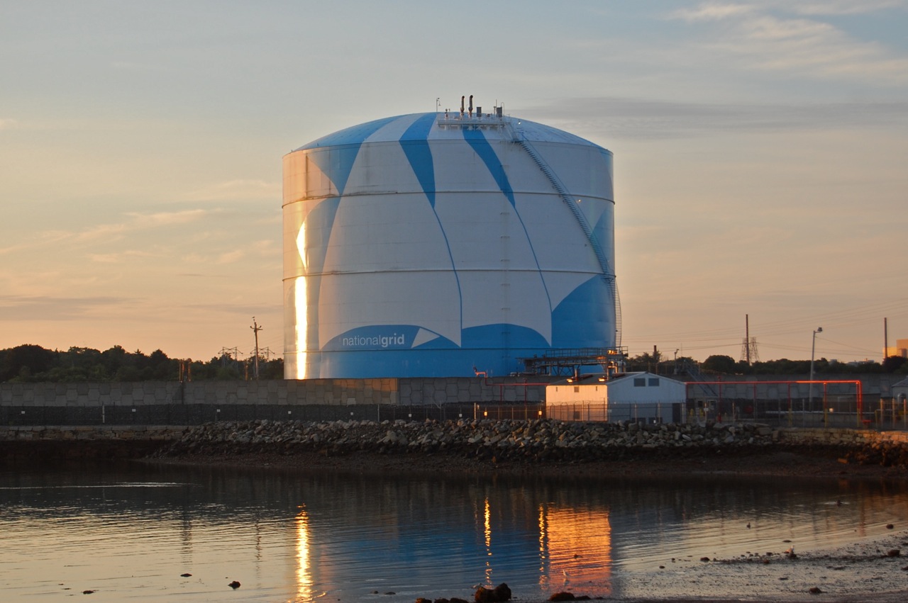 A National Grid LNG storage tank at dusk, reflecting in the water at a coastal terminal facility. Photo: Wikimedia Commons / CC BY-SA 3.0