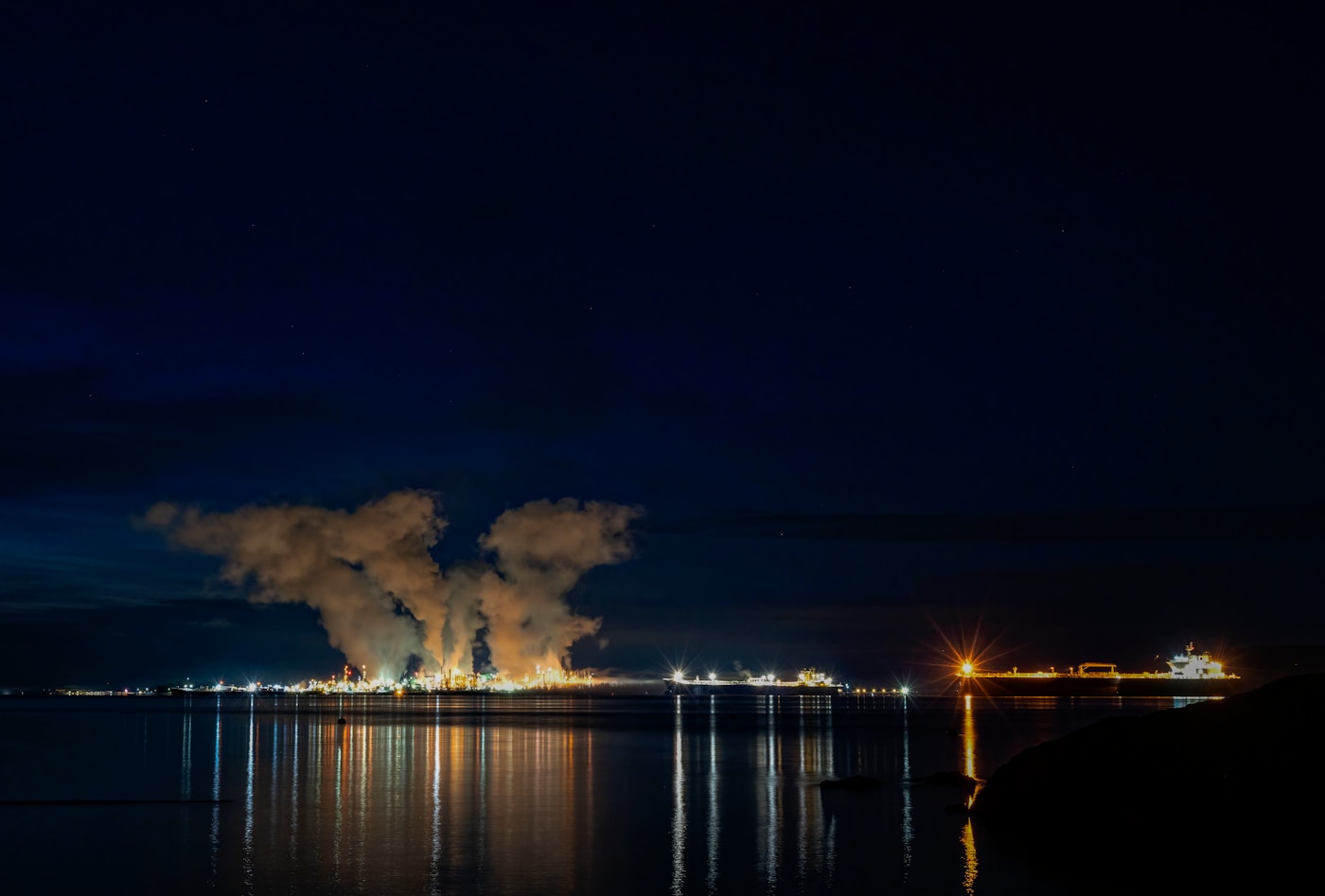 Gas processing plant and industrial facility lit up at night near a waterfront, representative of Gulf energy infrastructure under threat from Iranian drone attacks