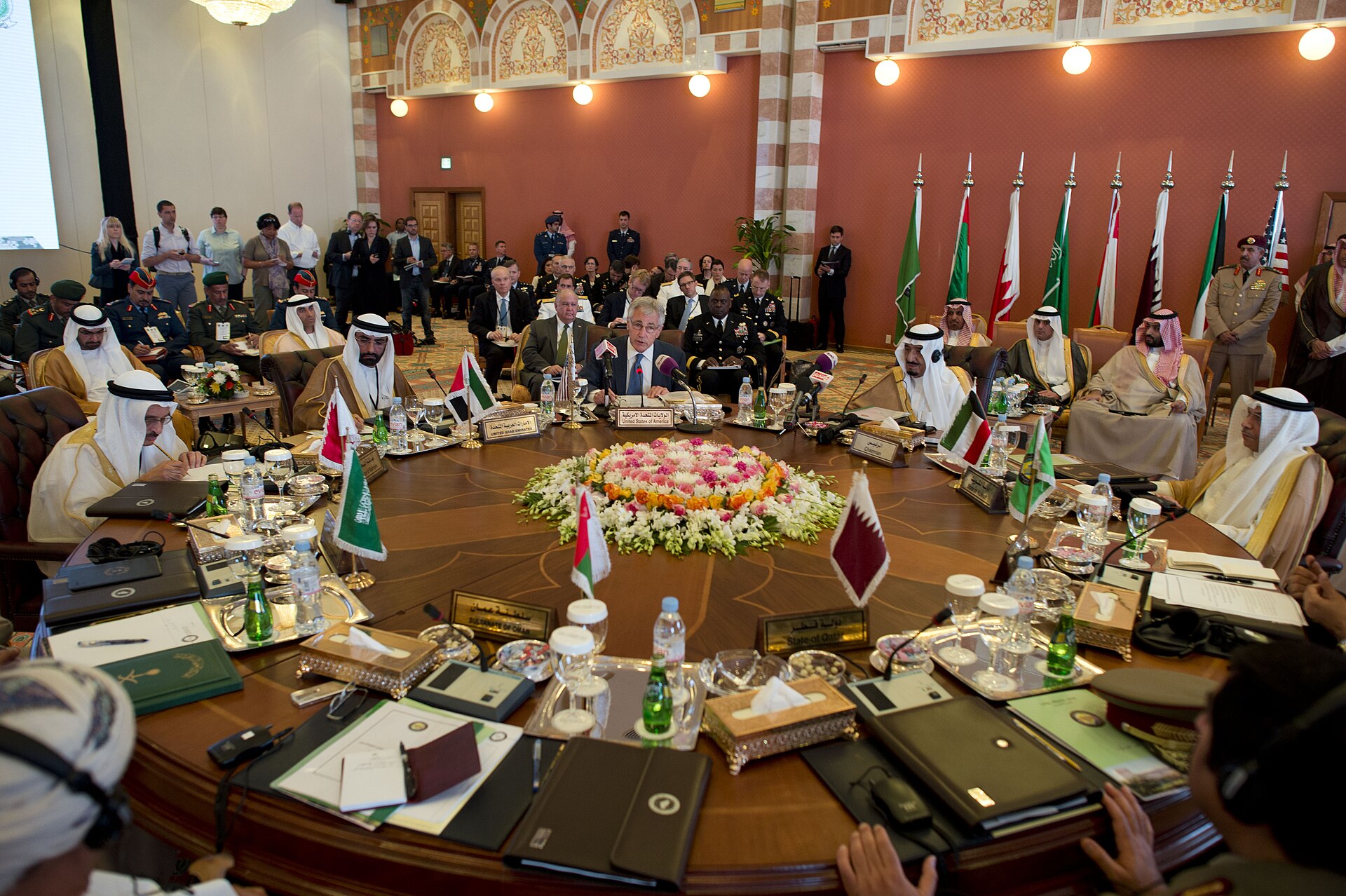 US Defense Secretary Chuck Hagel speaks at the Gulf Cooperation Council defense ministerial conference in Jeddah, Saudi Arabia, with GCC defense ministers seated around a round table with national flags. Photo: US Department of Defense / Public Domain