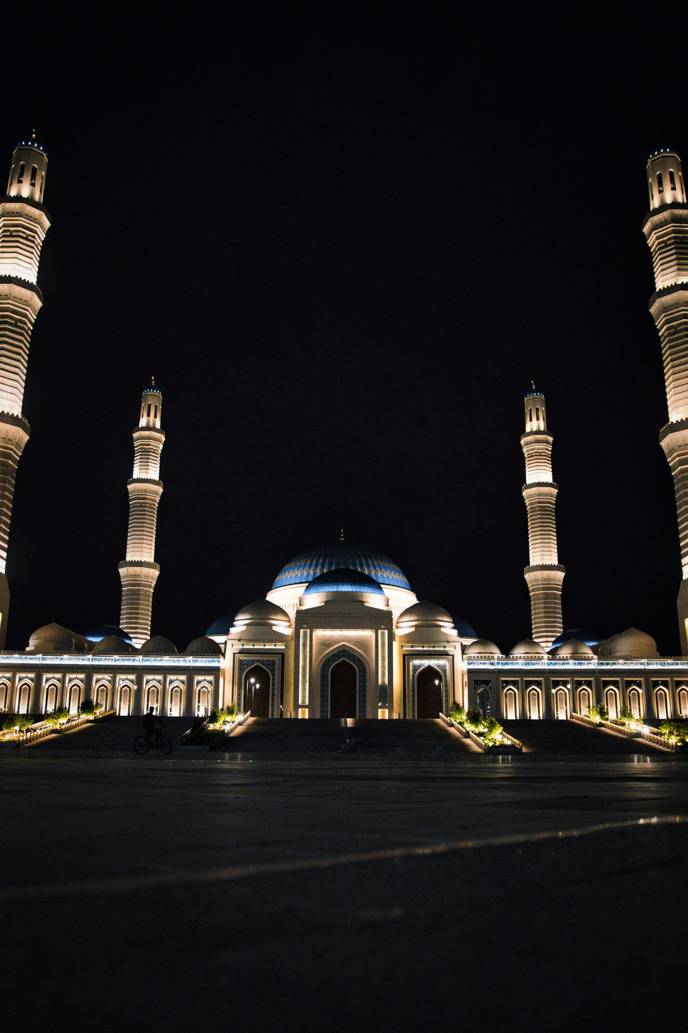 A grand mosque illuminated at night with four tall minarets, symbolizing the Eid al-Fitr celebrations that continue across Saudi Arabia despite the Iran war