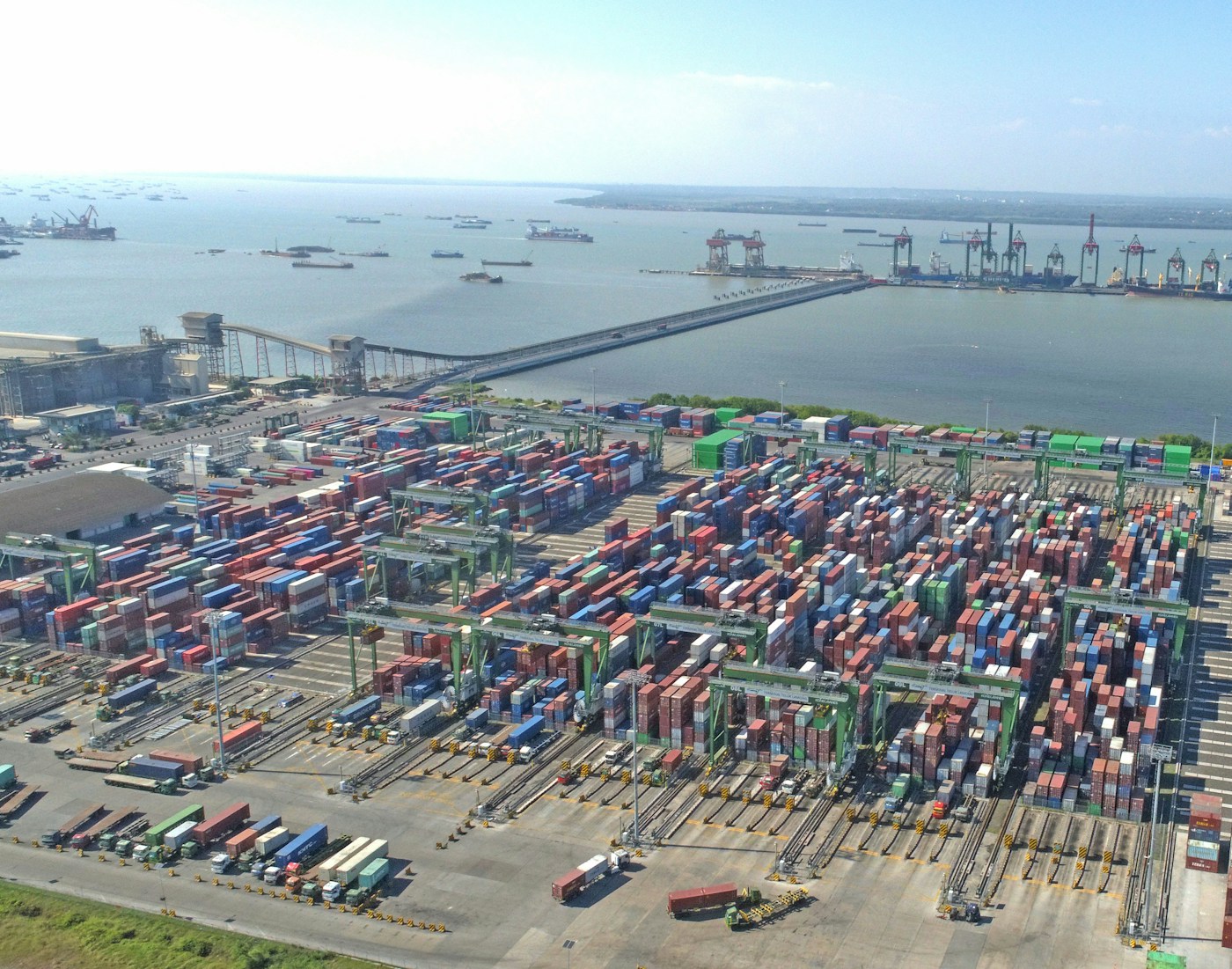 Aerial view of a busy container port with hundreds of shipping containers and cargo cranes loading vessels