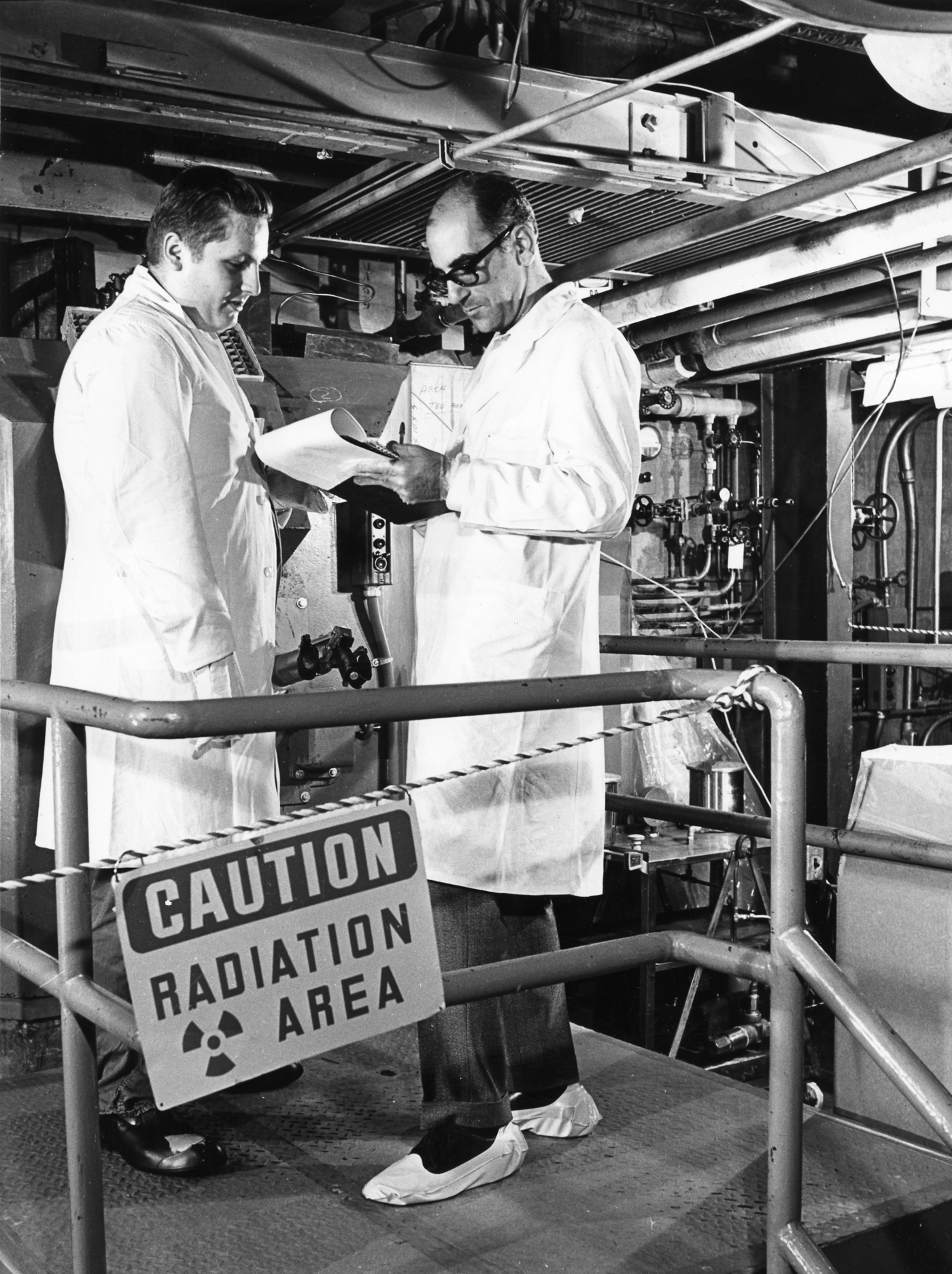 IAEA safeguards inspectors conducting radiation monitoring near a nuclear facility caution sign. Photo: IAEA / CC BY-SA 2.0