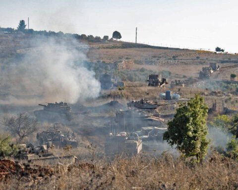 Israeli armored vehicles and tanks advance through southern Lebanon during ground operations, with smoke rising from the hillside. Photo: IDF / Wikimedia Commons / CC BY-SA 3.0
