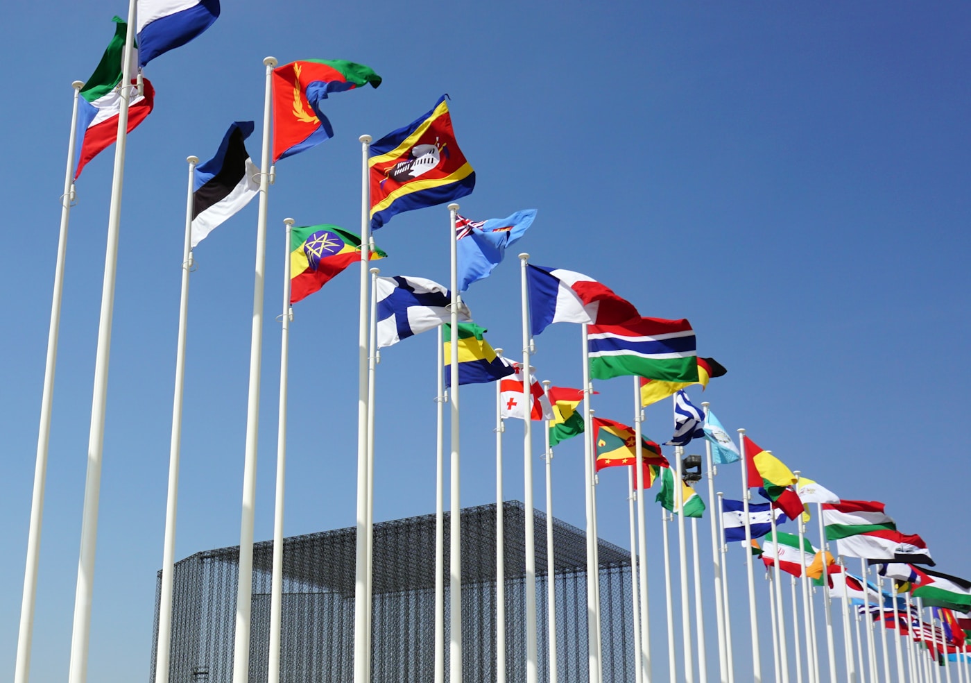 International flags flying at a diplomatic summit venue, symbolizing multilateral cooperation between Gulf Cooperation Council member states