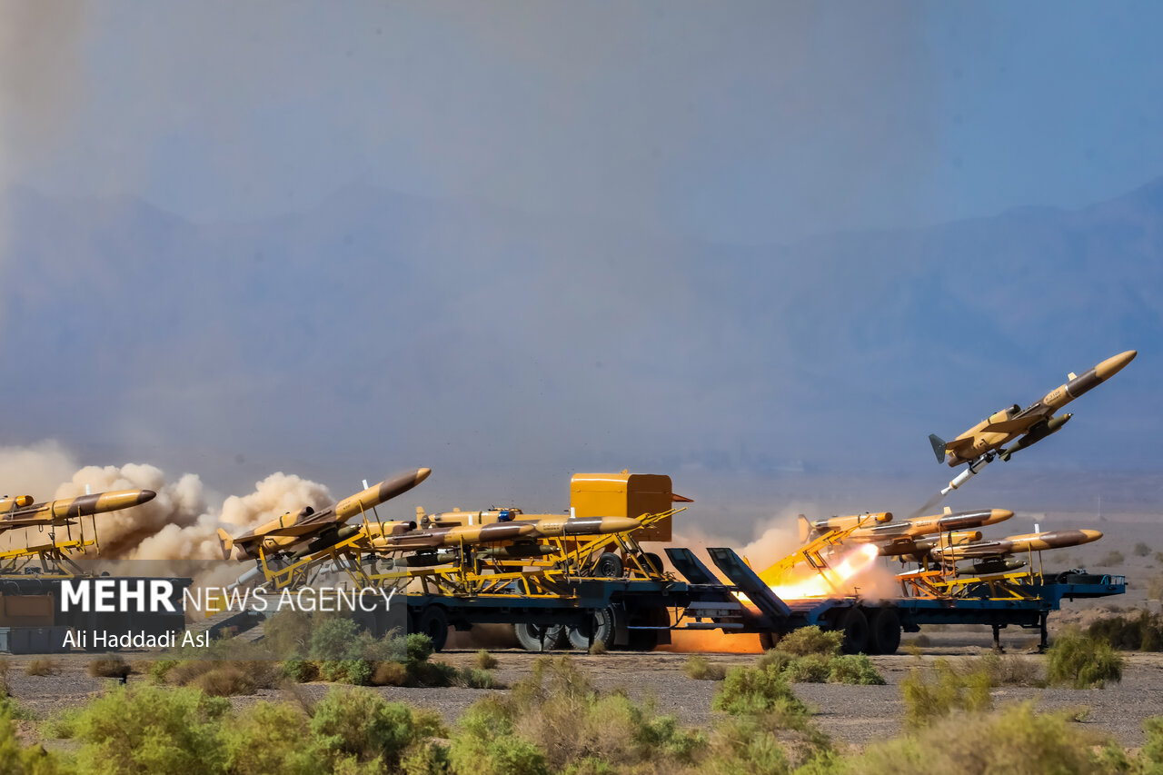 Mass drone launch during Iranian military exercise showing multiple unmanned combat aerial vehicles firing simultaneously from truck-mounted launchers. Photo: Mehr News Agency / CC BY 4.0