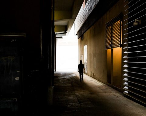 A shadowy figure walks through a dark urban corridor, evoking the covert proxy networks Iran has activated across the Gulf states during the 2026 war