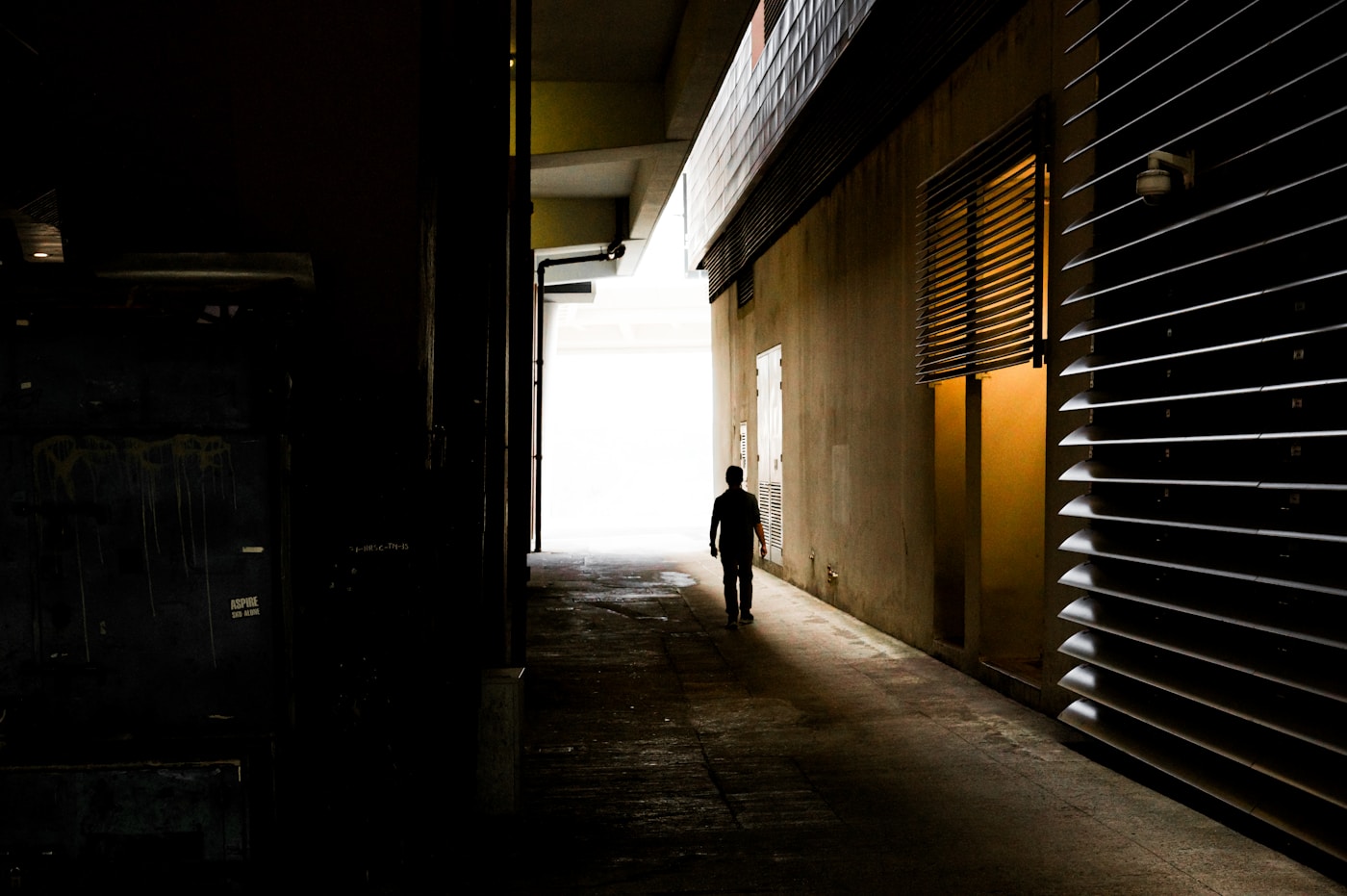 A shadowy figure walks through a dark urban corridor, evoking the covert proxy networks Iran has activated across the Gulf states during the 2026 war