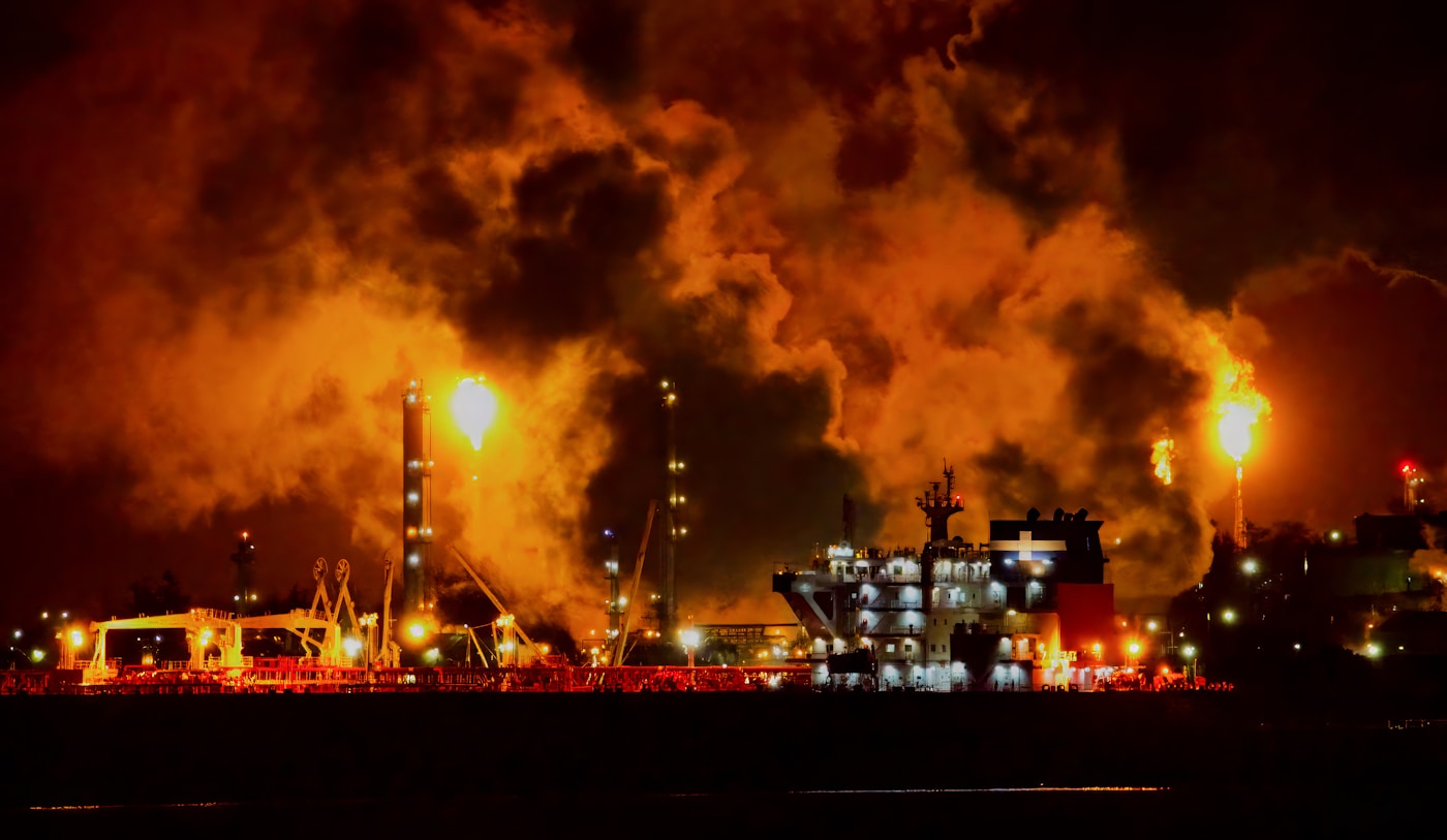 Oil facility engulfed in flames and toxic smoke at night during the Iran war, illustrating environmental damage to Gulf petroleum infrastructure