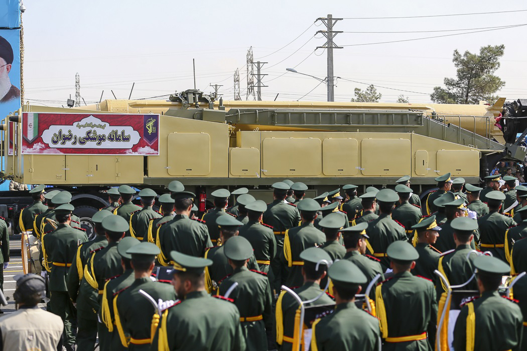 IRGC officers watch a ballistic missile launcher pass during a military parade in Tehran with a portrait of Supreme Leader Khamenei visible in the background