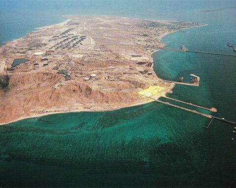 Aerial view of Kharg Island showing oil storage tanks, gas flares, and tanker loading piers in the Persian Gulf. Photo: National Iranian Oil Company / Public Domain