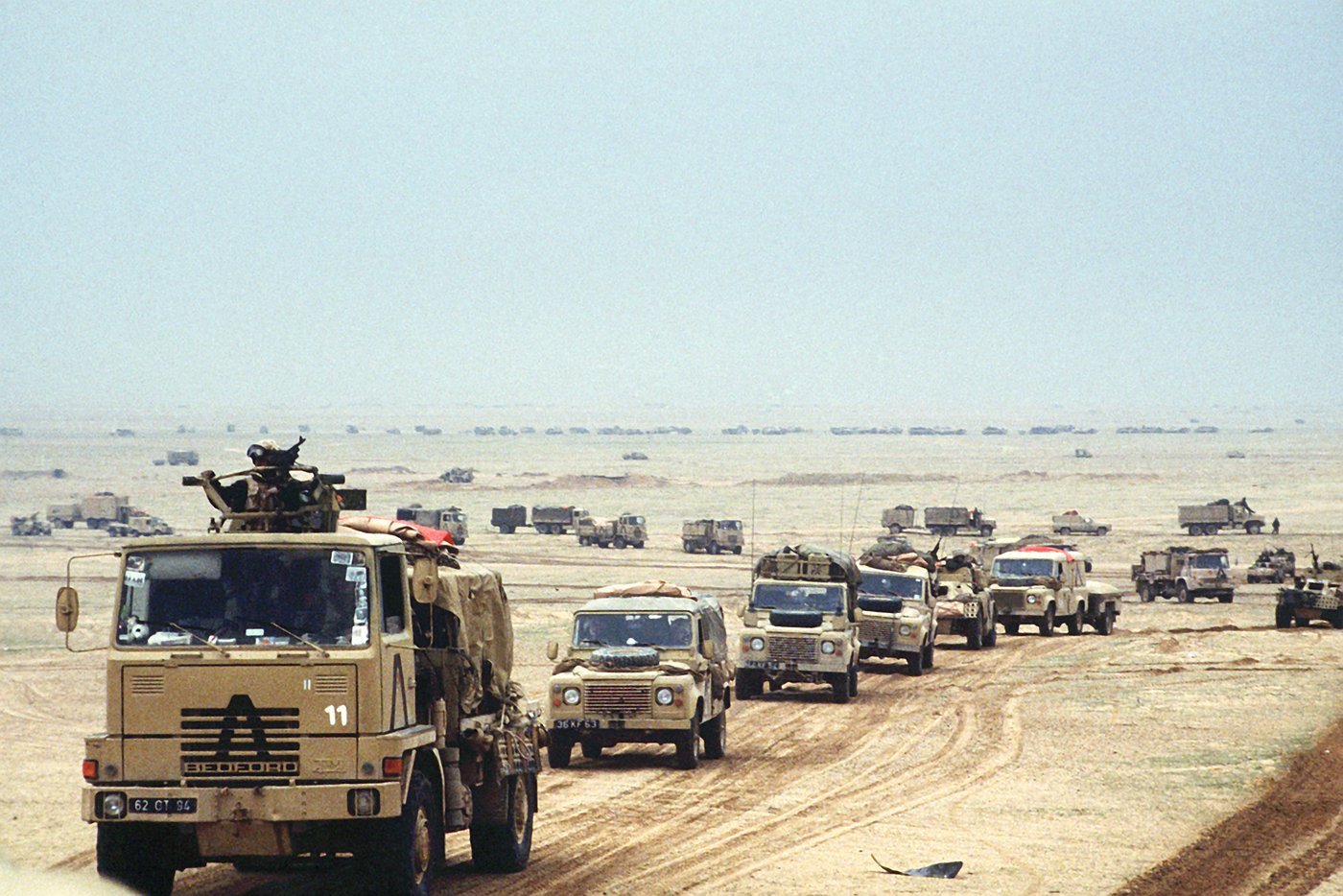 A military convoy moves through the flat desert terrain along the Iraq-Saudi Arabia border corridor during the Gulf War. Photo: UK Ministry of Defence / Public Domain