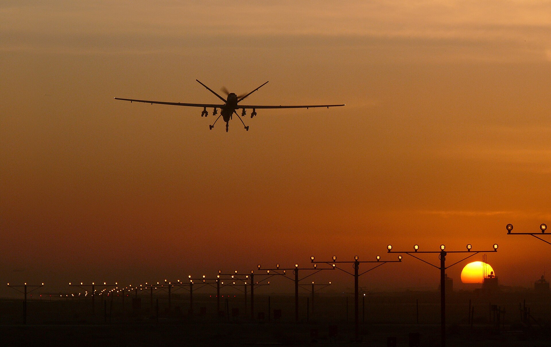 MQ-9 Reaper military drone silhouetted against sunset while landing at an airbase. Photo: UK MOD / OGL v1.0