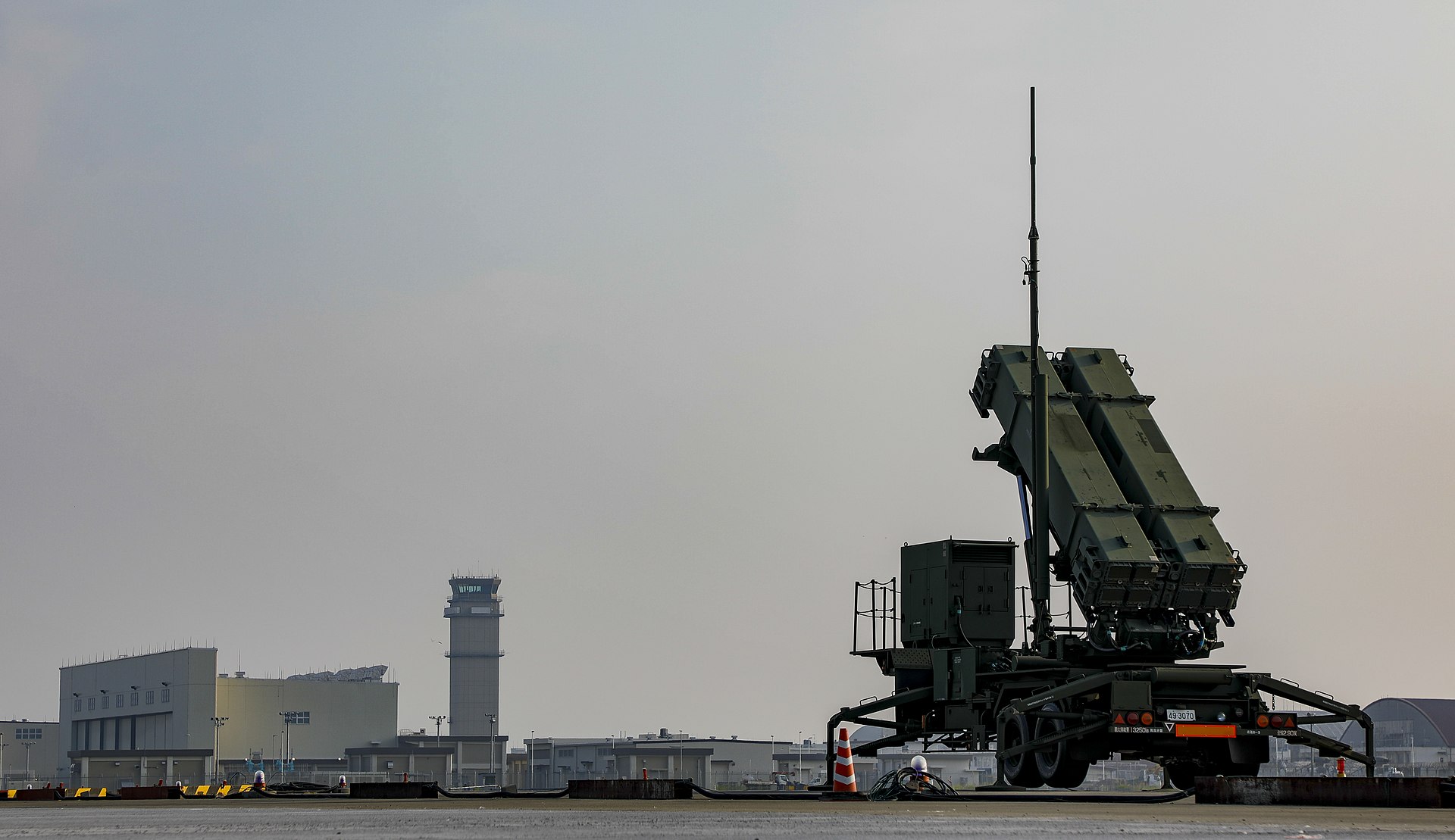 MIM-104 Patriot missile defense system deployed in defensive posture at an air base, with launcher canisters elevated and ready to intercept incoming ballistic missiles and drones