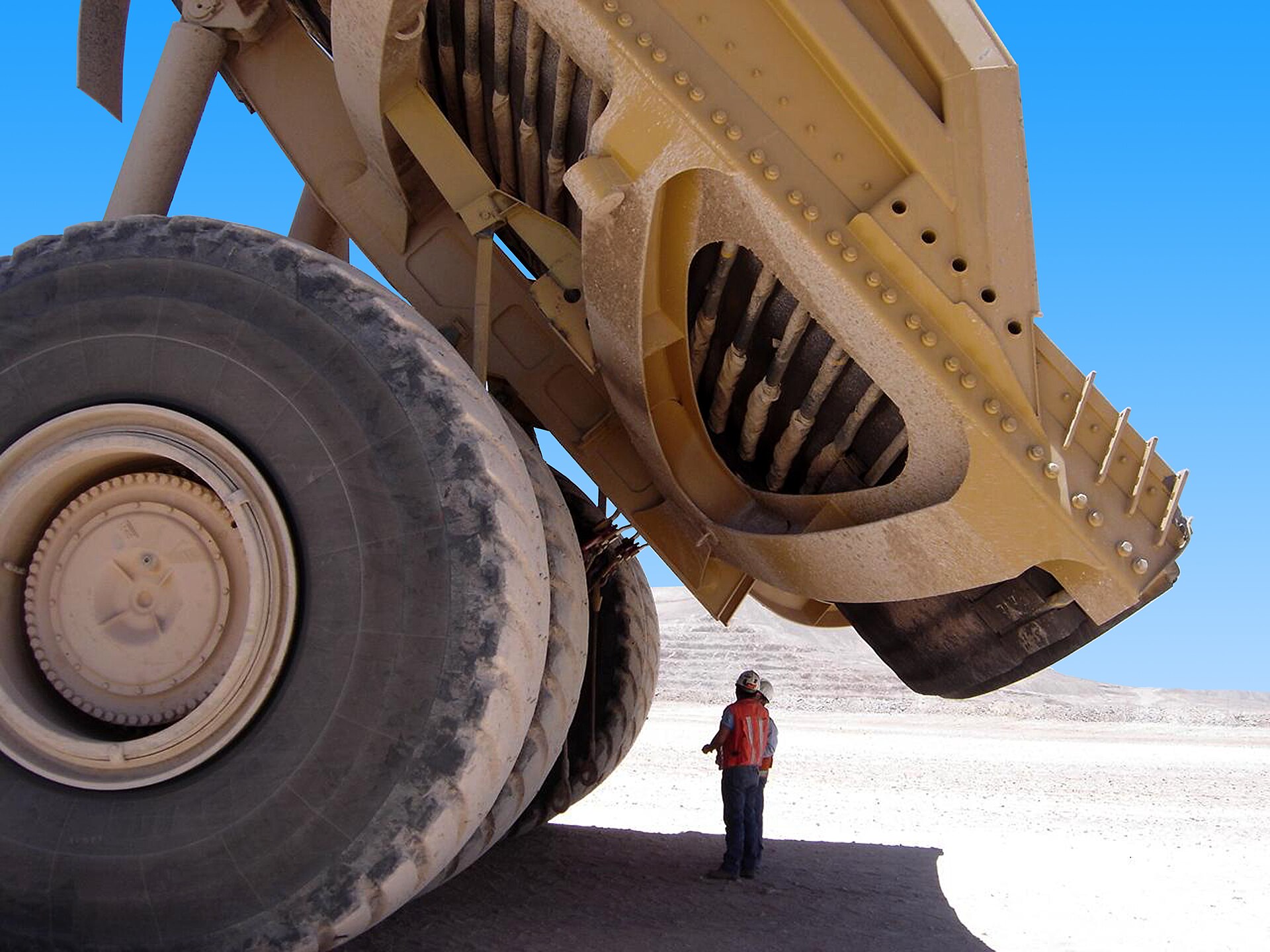 A Caterpillar 797 haul truck dwarfs a worker at an open-pit mine