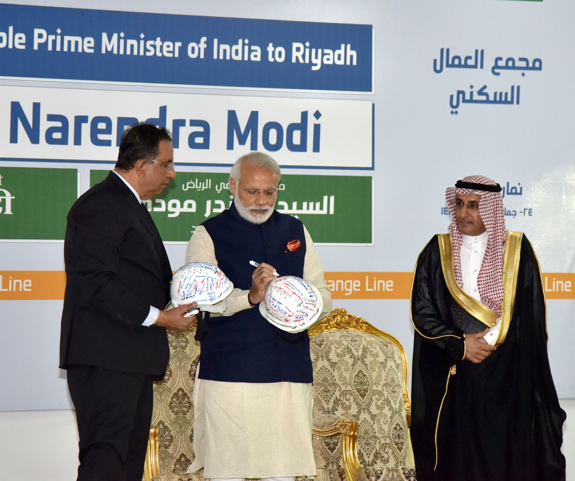 Prime Minister Narendra Modi signing a construction helmet at an L&T Indian workers residential complex in Riyadh, Saudi Arabia in 2016, illustrating the Indian diaspora presence in the Kingdom.