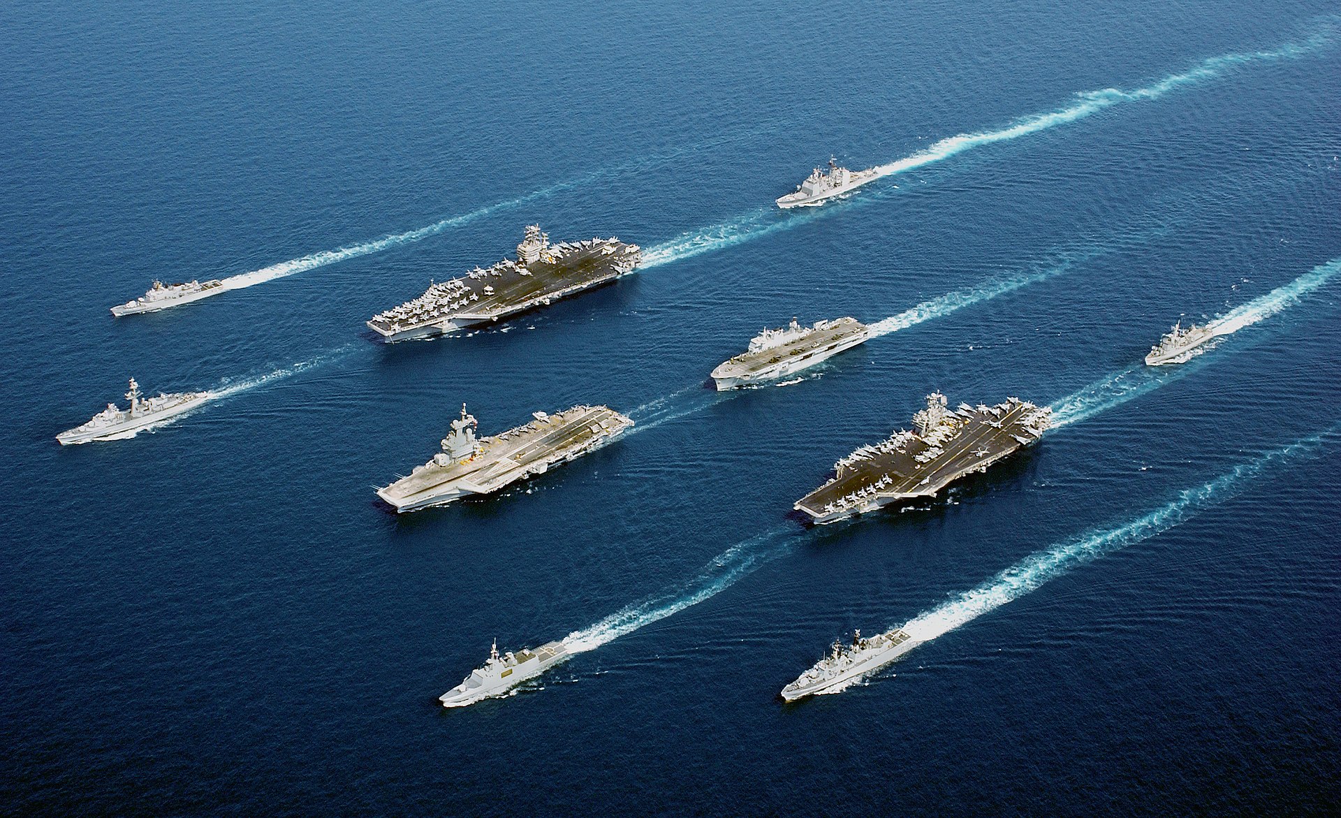 Naval vessels from multiple nations move in formation during a joint exercise at sea including aircraft carriers and escort ships. Photo: US Navy / Public Domain