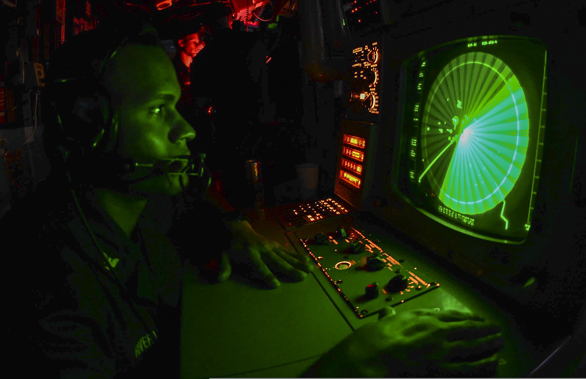 A US Navy operations specialist monitors a radar console aboard a guided missile cruiser in the Persian Gulf, tracking incoming drones and missiles.