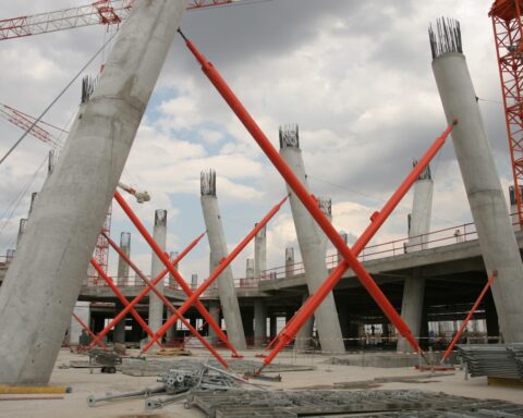 Massive concrete pillars and construction cranes at a stalled megaproject construction site resembling NEOM Trojena infrastructure work