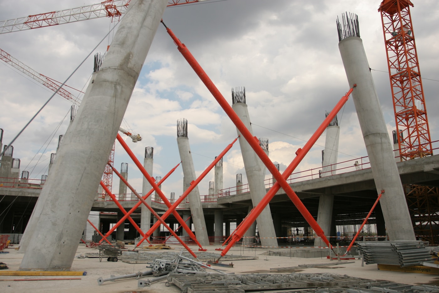 Massive concrete pillars and construction cranes at a stalled megaproject construction site resembling NEOM Trojena infrastructure work