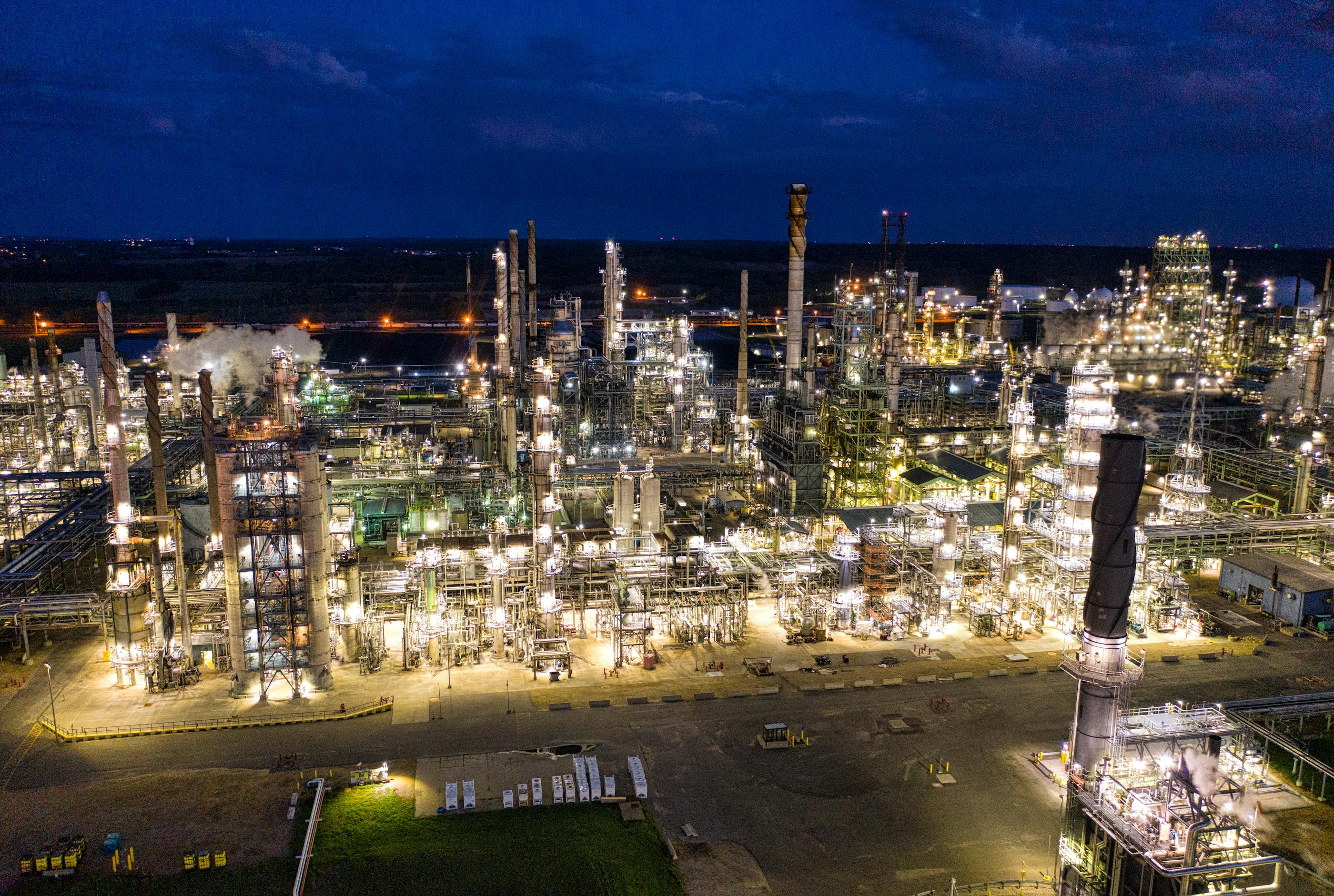 Oil refinery complex illuminated at night, representative of the downstream processing capacity African producers are racing to build