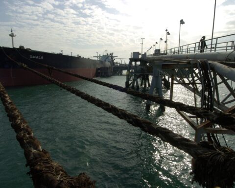 Oil tanker Omala moored at the Al Basrah Oil Terminal in the Persian Gulf, with heavy mooring ropes and industrial loading infrastructure visible