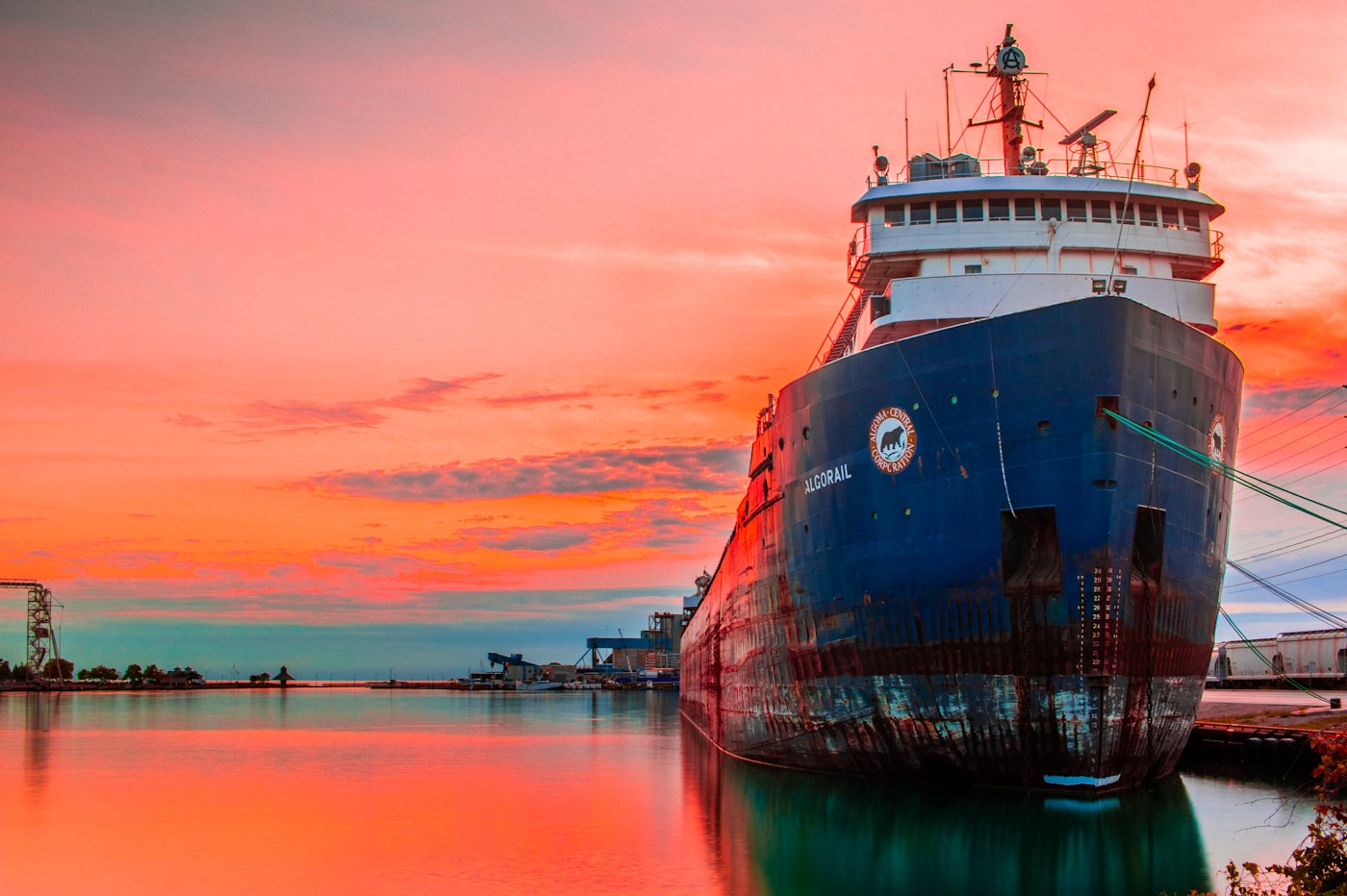 A large cargo vessel moored at port at sunset, illustrating the maritime shipping disruptions caused by the Strait of Hormuz closure