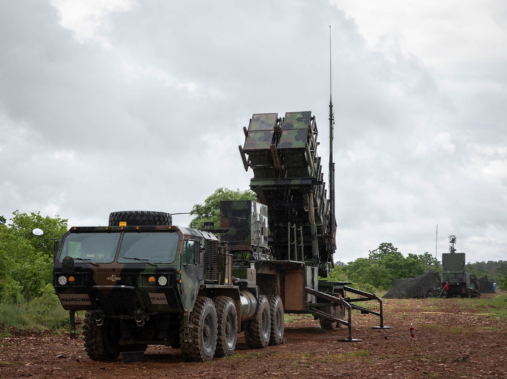 A U.S. Army MIM-104 Patriot missile defense system deployed in a field position with launcher elevated and radar antenna visible