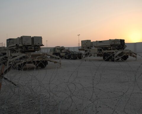 PAC-2 and PAC-3 Patriot missile launchers deployed at an air base in Southwest Asia at sunset behind concertina wire