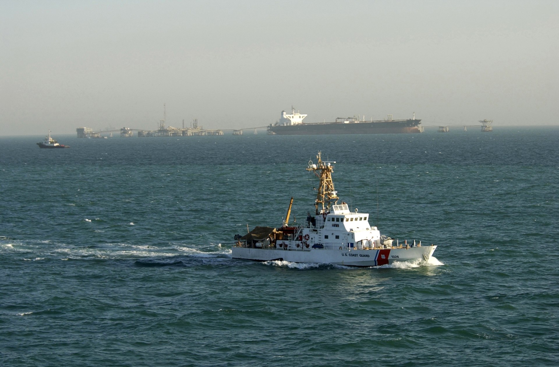 US Coast Guard cutter patrolling near an oil terminal in the Persian Gulf as a supertanker loads crude oil. Photo: US Navy / Public Domain