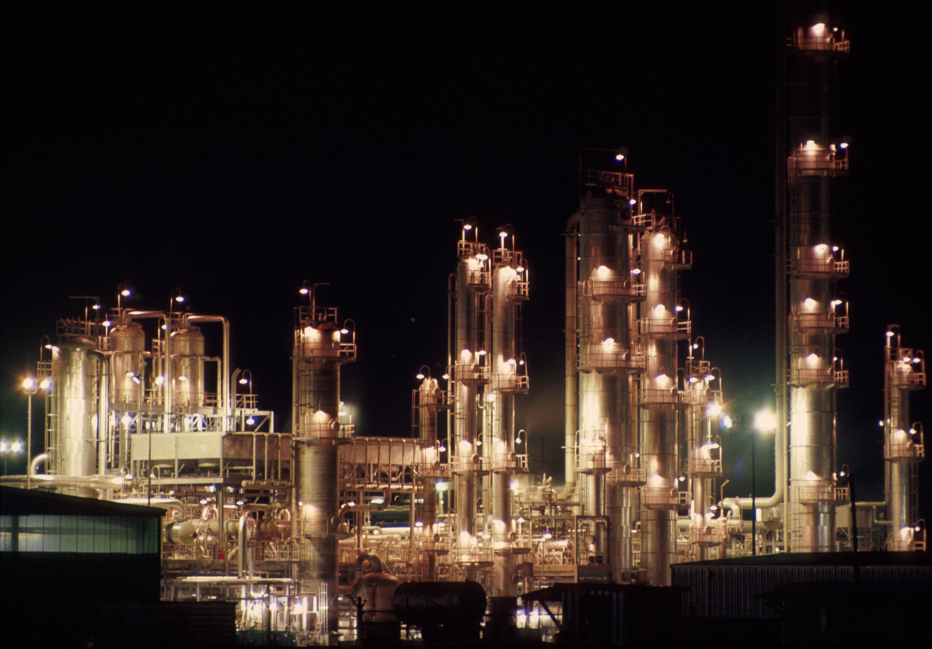 Petrochemical refinery illuminated at night representing the vulnerable energy infrastructure at the center of the Iran war oil price crisis. Photo: Wikimedia Commons / CC BY-SA 4.0