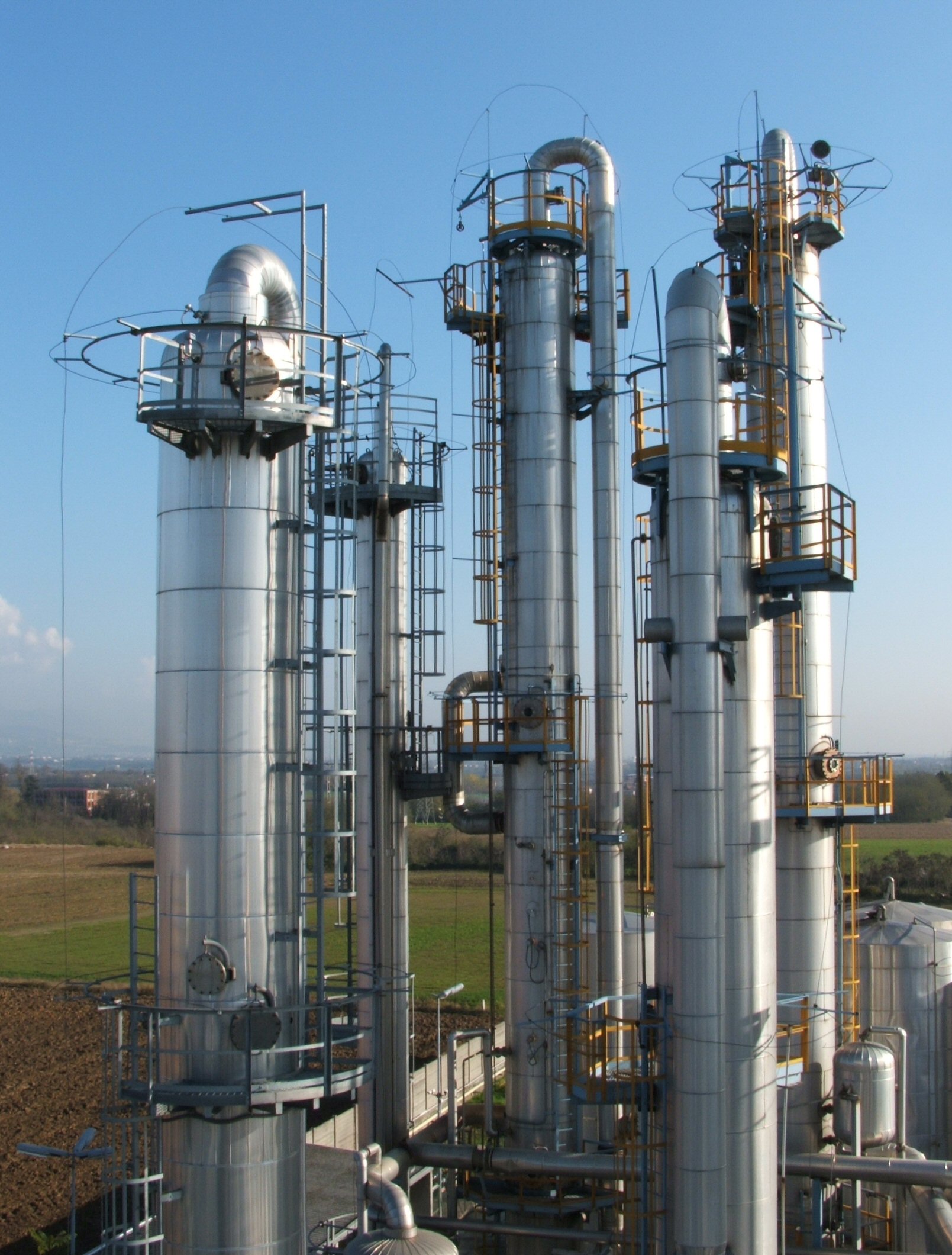 Petroleum distillation columns at an oil refinery, representing the complex infrastructure required to convert crude oil into usable fuels