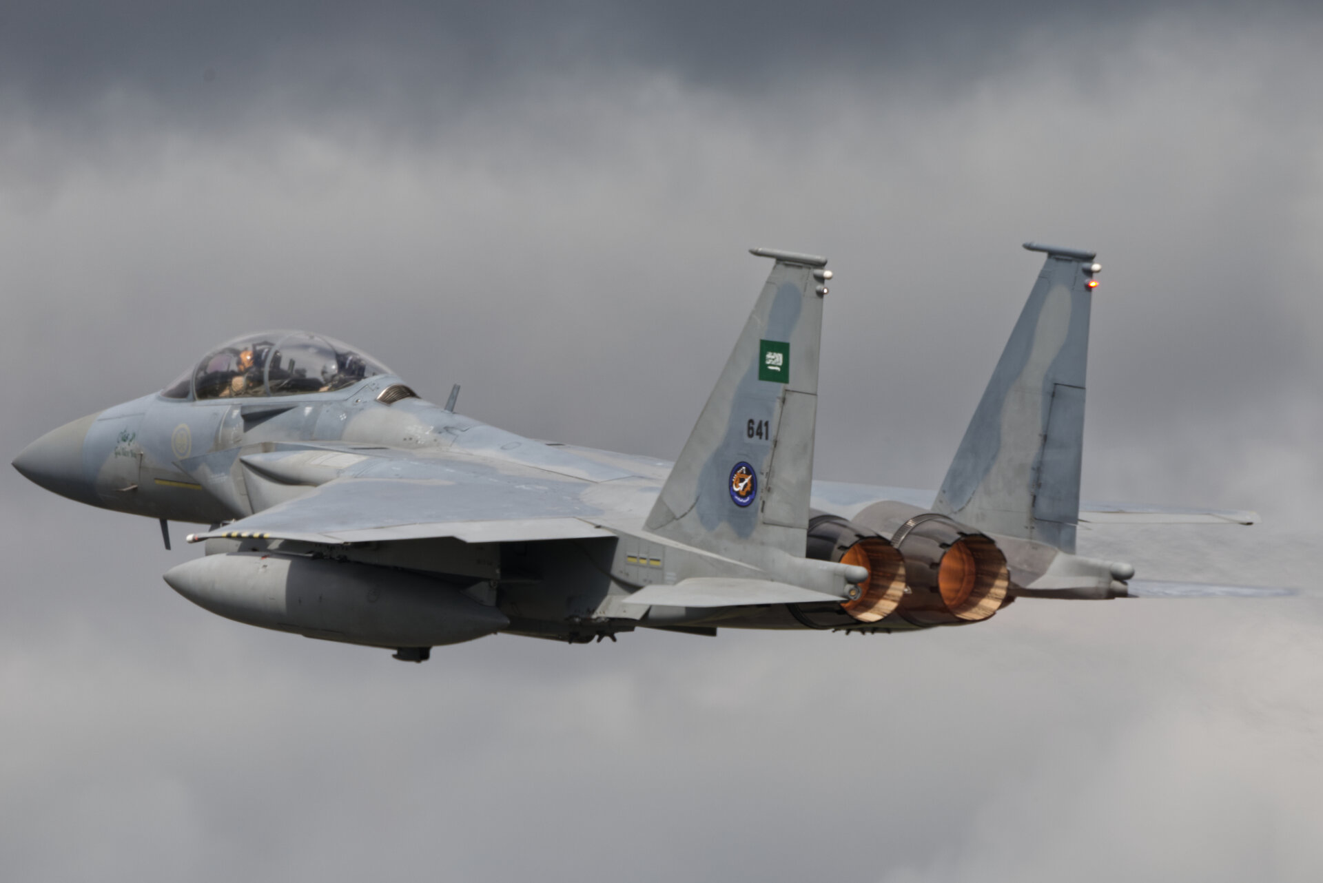A Royal Saudi Air Force Boeing F-15SA Eagle fighter jet in flight with afterburners lit, showing Saudi military markings
