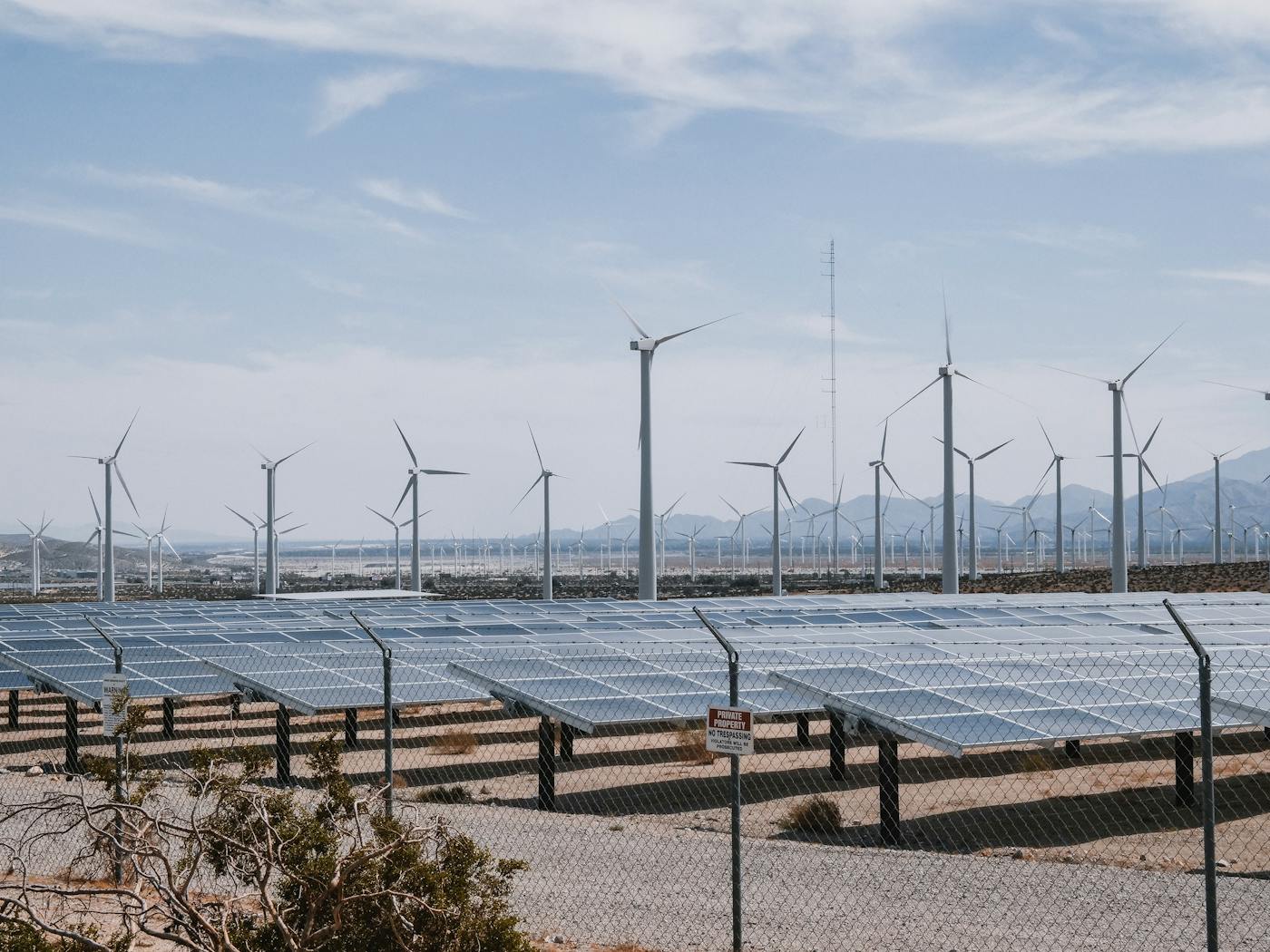 Solar panels and wind turbines in a desert landscape representing Saudi Arabia renewable energy expansion