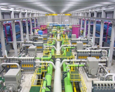 Interior of a large-scale reverse osmosis desalination plant showing green industrial pipes and membrane filtration racks used to produce drinking water from seawater. Photo: Wikimedia Commons / CC BY-SA 3.0