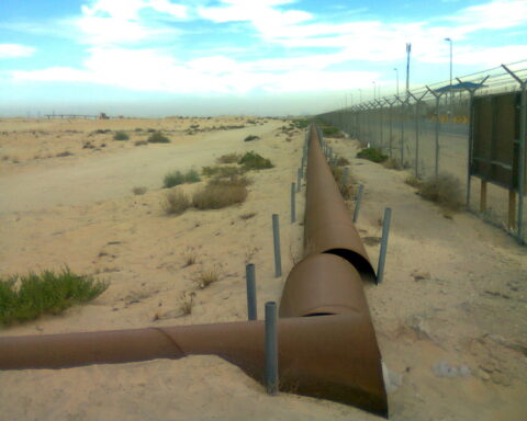 Oil pipeline infrastructure crossing the Saudi Arabian desert near Jubail, with security fencing along the route