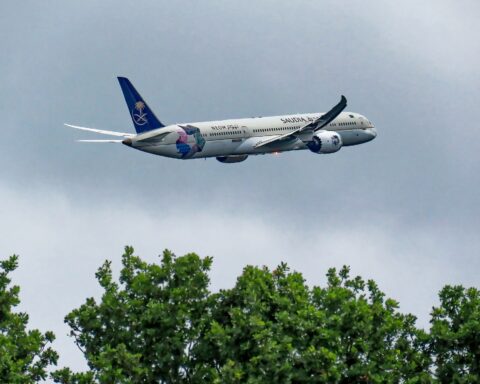 Saudia Boeing 787-10 Dreamliner with NEOM livery in flight over London, representing Saudi aviation connectivity now severed by the Iran war