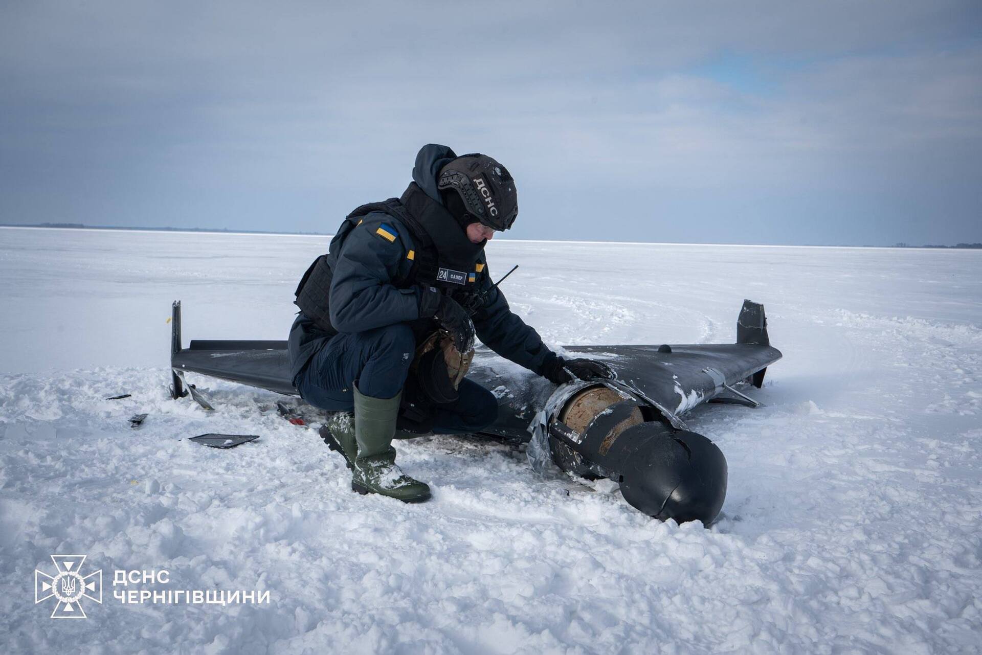 A Ukrainian emergency services worker examines the remains of a downed Iranian Shahed drone in Chernihiv Oblast, February 2026, showing the expertise Ukraine has developed in countering these weapons. Photo: DSNS Chernihiv / CC BY 4.0