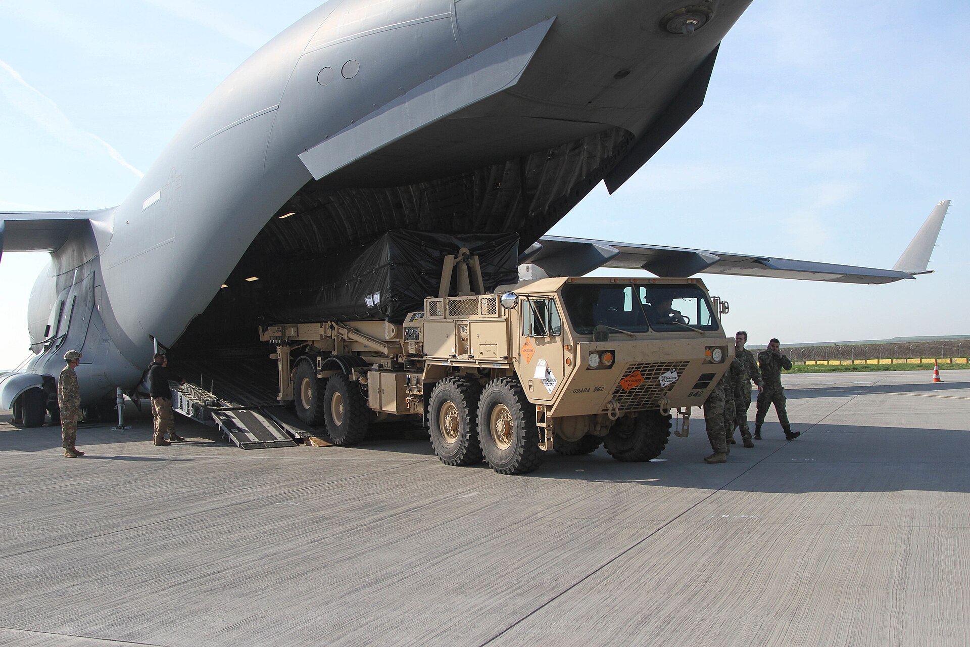 A THAAD missile defense launcher being offloaded from a U.S. Air Force C-17 Globemaster III transport aircraft, representing the advanced air defense systems deployed to protect Gulf states from Iranian missile attacks