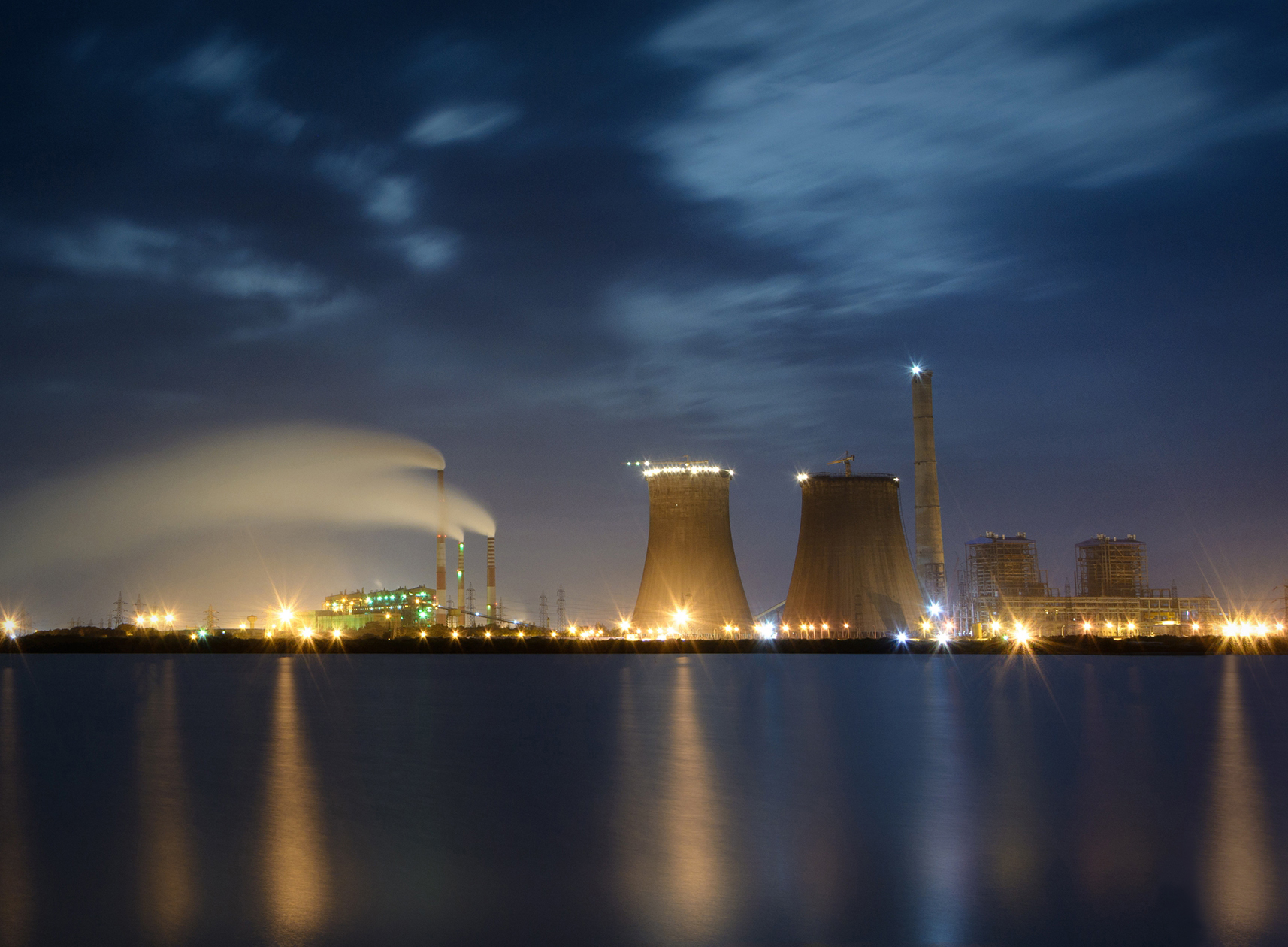 A thermal power station at night with cooling towers and illuminated infrastructure. Trump threatened to destroy similar facilities across Iran. Photo: Wikimedia Commons / CC BY-SA 2.0
