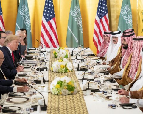 President Donald Trump and Crown Prince Mohammed bin Salman face each other across a bilateral meeting table at the G20 summit in Osaka, with US and Saudi flags behind them