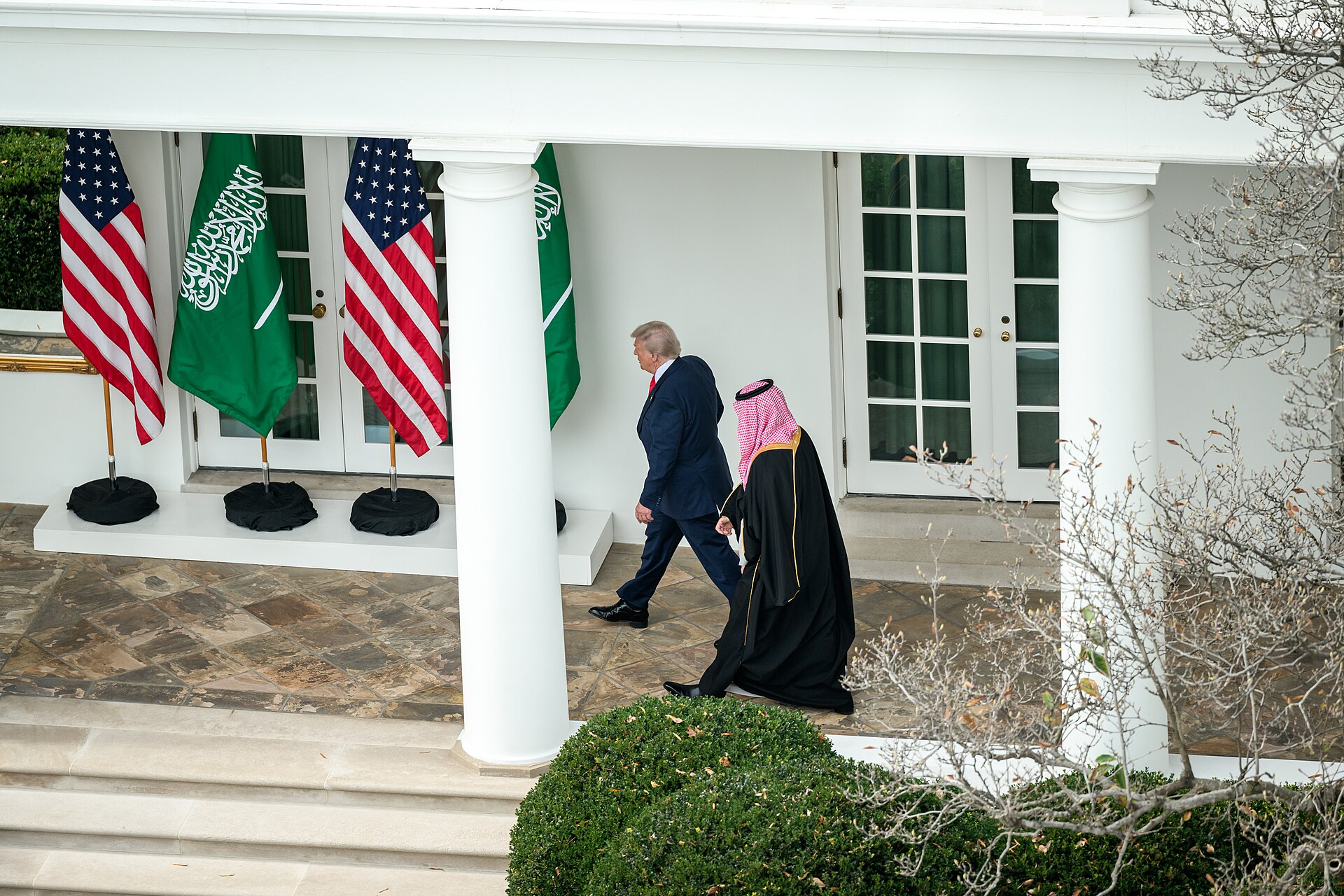 President Donald Trump and Crown Prince Mohammed bin Salman walking at the White House South Portico with US and Saudi flags, November 2025. Photo: White House / Public Domain