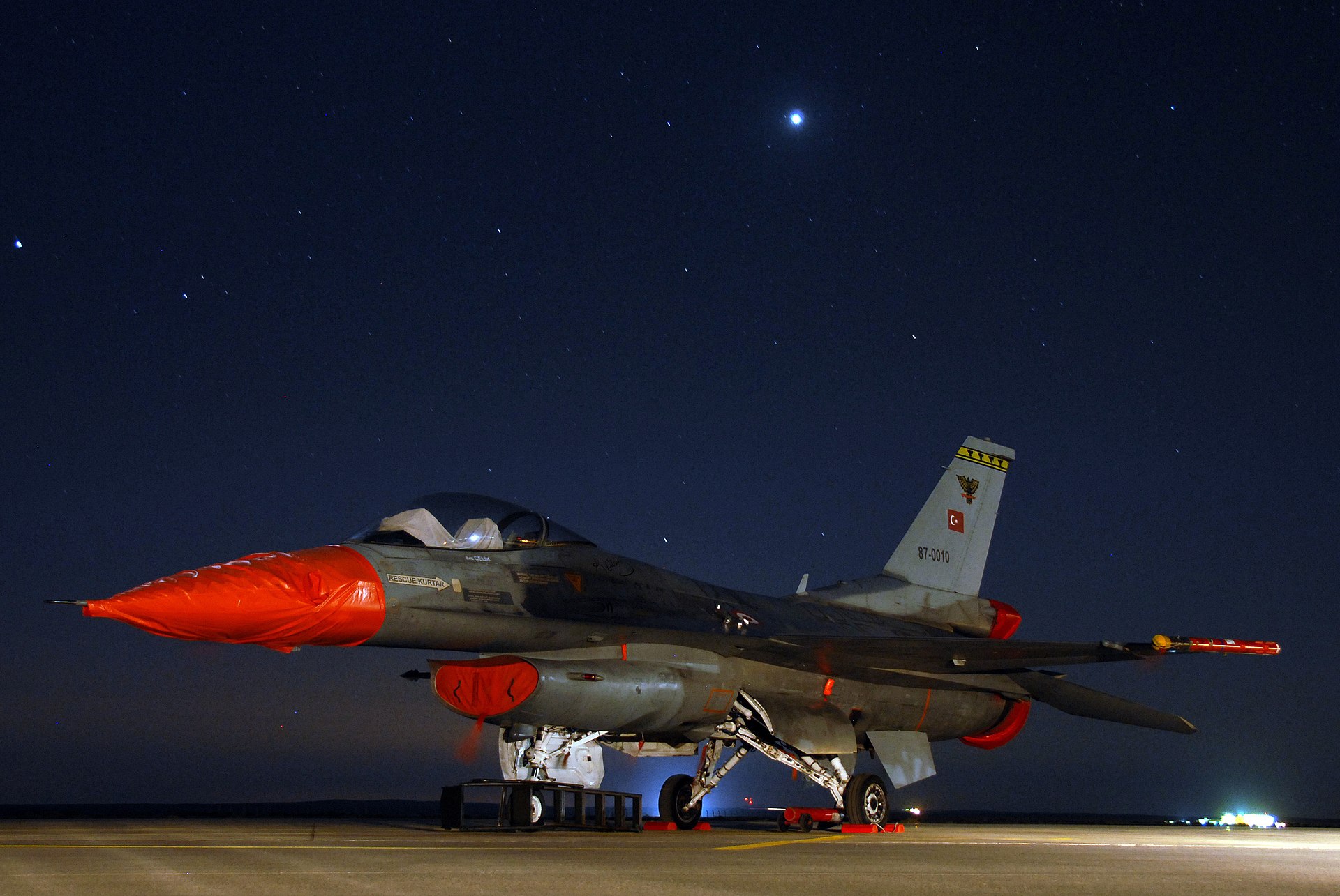 A Turkish Air Force F-16 Fighting Falcon fighter jet parked on the tarmac at night with Turkish military markings visible on the tail