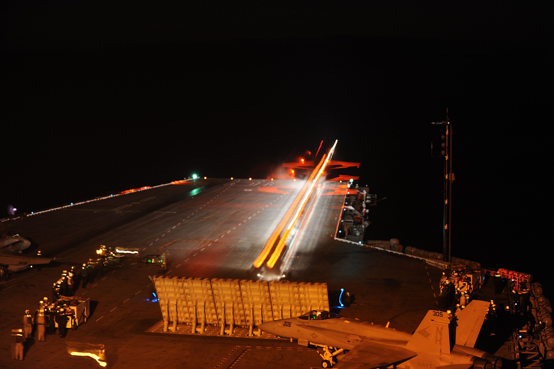 A fighter jet launches from the flight deck of USS Nimitz during night operations, representing the US military commitment at stake in the Saudi defense pact debate. Photo: US Navy / Public Domain